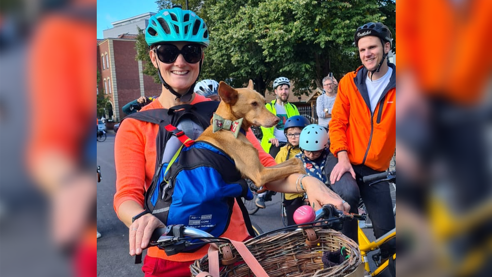 Libby Bowles on her bike carrying Pip in a backpack on her front.