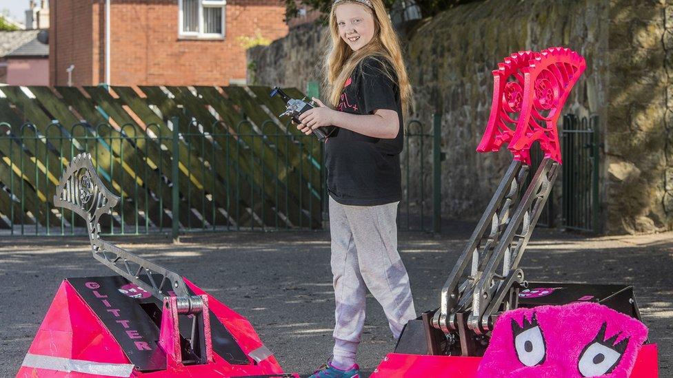 Eleven-year-old April Prince with two robots she engineered