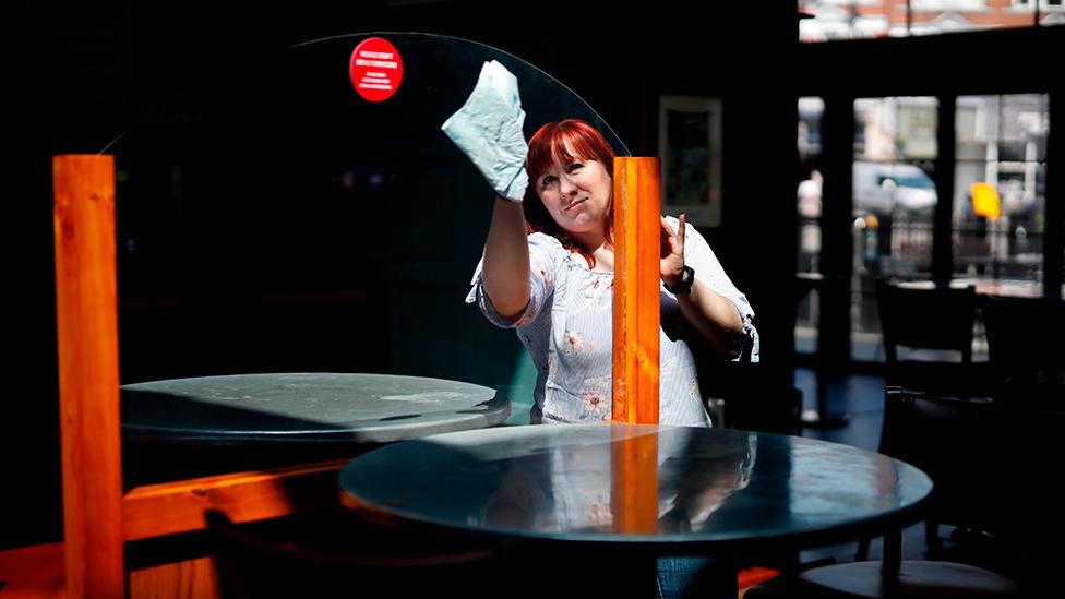 Pub worker cleans screen between tables