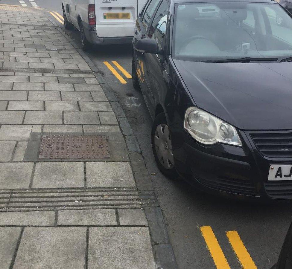 Double yellow lines painted around a black car