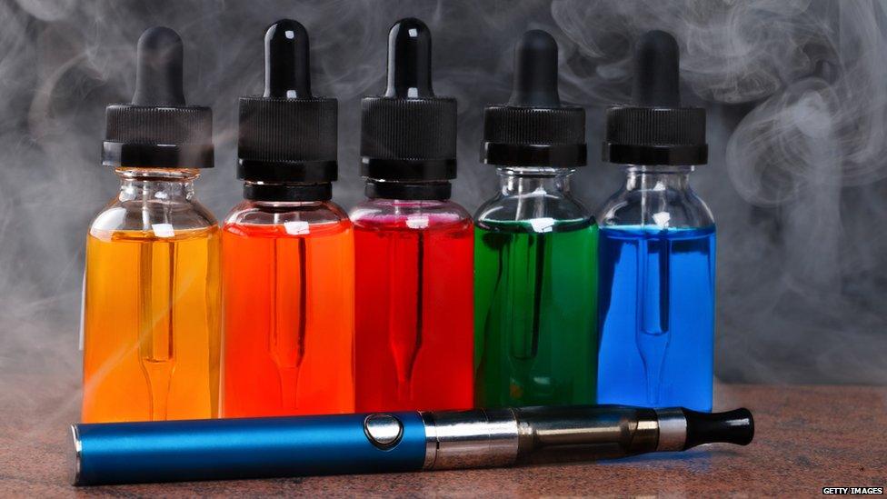 An e-cigarette and bottles of e-liquid