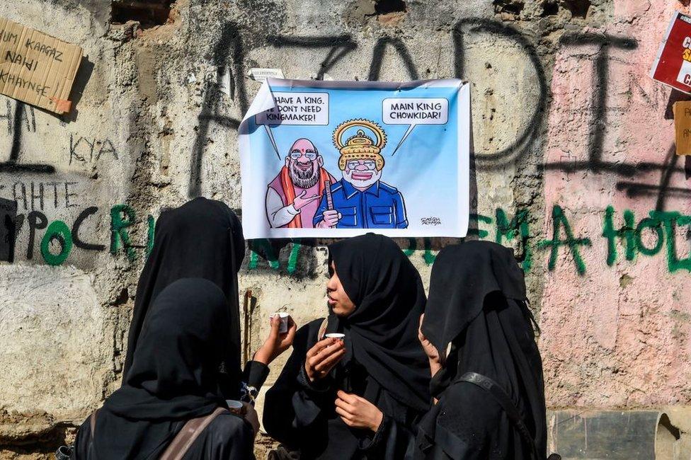 Muslim women drink chai (tea) on a street in front of a wall covered with posters and graffitis to protest against India's new citizenship law, during a demonstration in Mumbai on January 30, 2020.