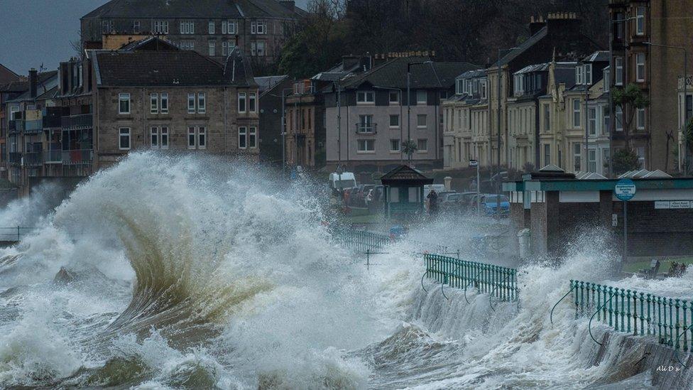 Huge waves crashing over the barrier near houses in Inverclyde