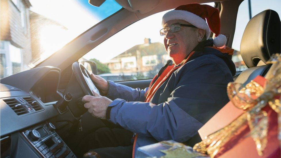 Man with Santa's hat on driving a car