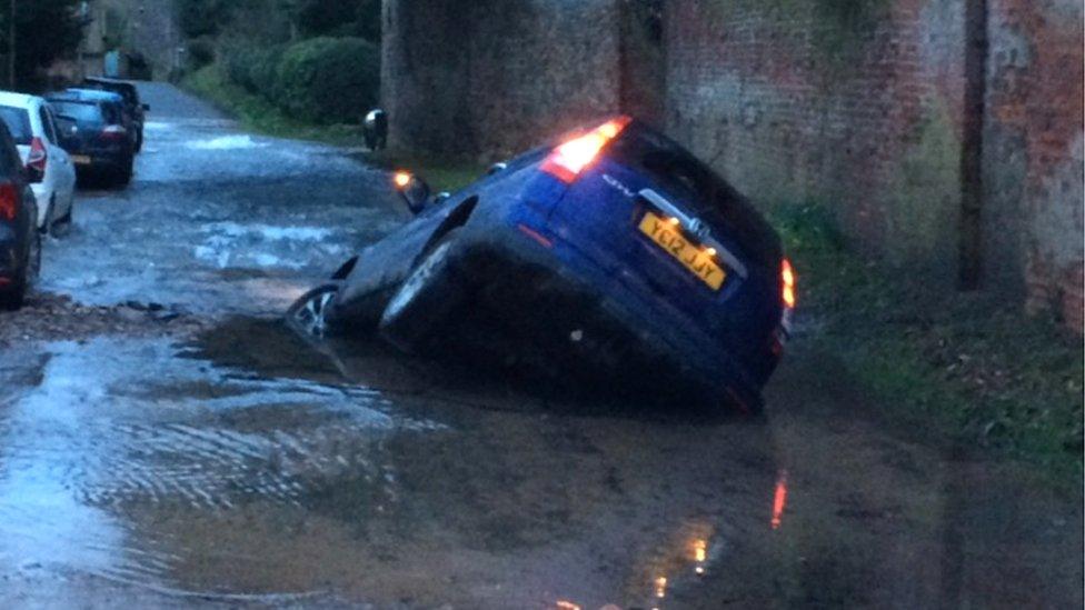 Car in a sinkhole created by a burst water main