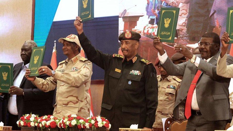 Sudan's Army chief Abdel Fattah al-Burhan (C R) and paramilitary commander Mohamed Hamdan Dagalo (C L) lift documents alongside civilian leaders