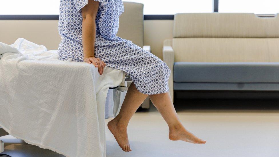 Female patient sitting at end of bed