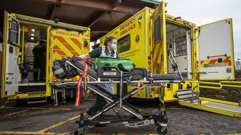 A paramedic working next to two ambulances