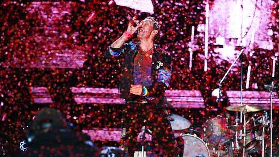 Coldplay's Chris Martin performs on stage as confetti falls.