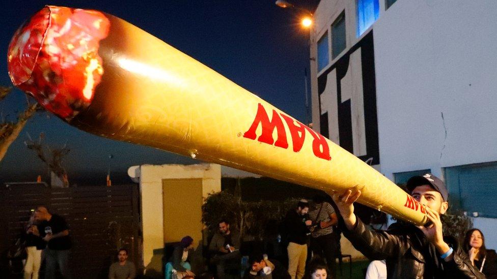 A supporter of the leader of the far-right Zehut political party Moshe Feiglin smokes a fake inflatable marijuana joint during a meeting in the Israeli city of Tel Aviv on 2 April 2019