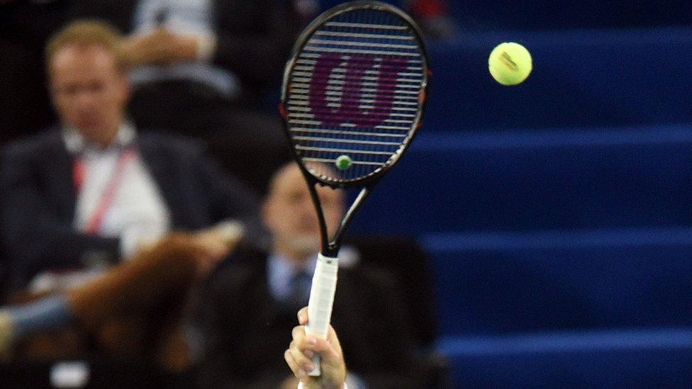 A cropped image of a tennis racquet and player's hand from a recent tennis game, for illustration purposes.