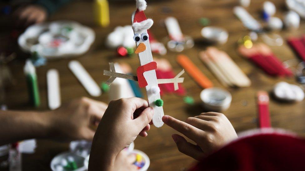 Child hands hold a homemade Christmas decoration