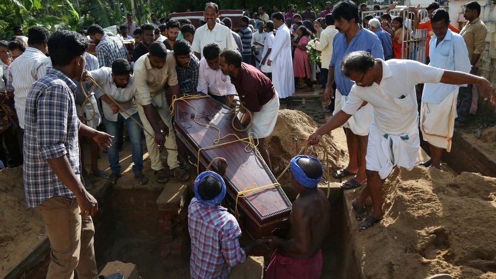 Men are lowering a coffin into a grave