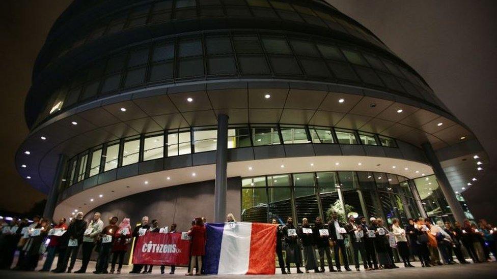 People holding candles create a human ring of unity around City Hall, London