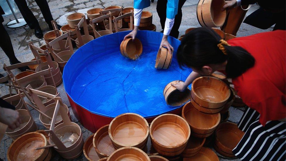 People fill wooden buckets with water during an event called uchimizu - which is meant to cool down the area, in Tokyo on July 23, 2018