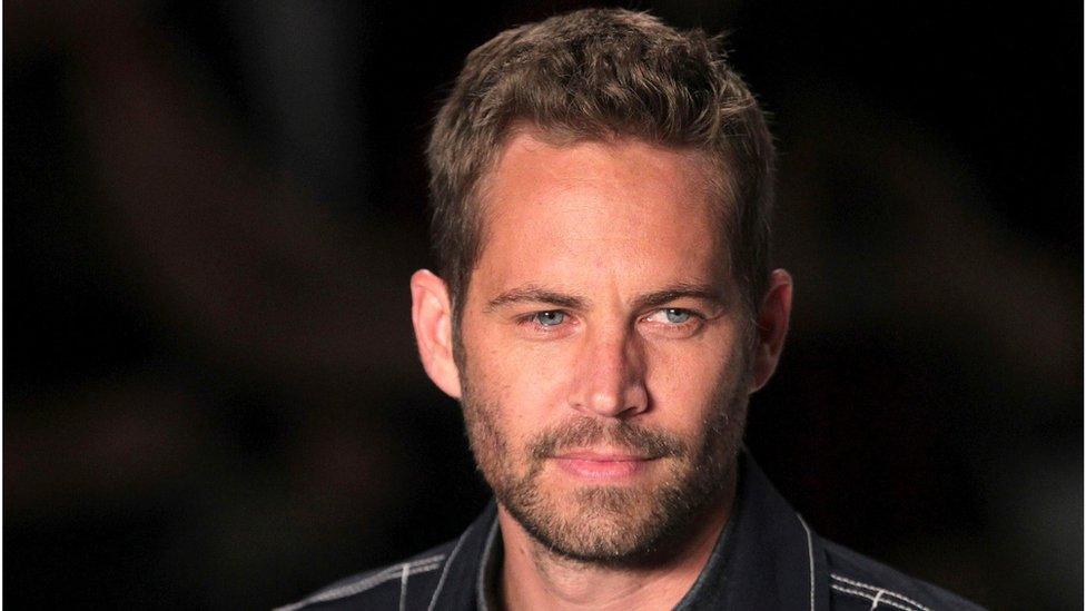 U.S. actor Paul Walker presents a creation from Colcci"s 2013/2014 summer collection during Sao Paulo Fashion Week in this March 21, 2013