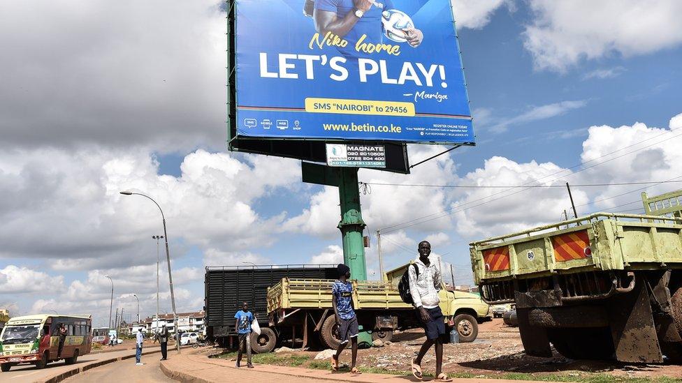 Boys walk under a billboard advertising a popular sports betting site in Nairobi's Kawangware suburb - November 2017