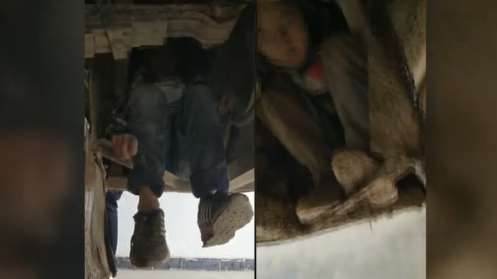 Two boys hiding under a bus in China