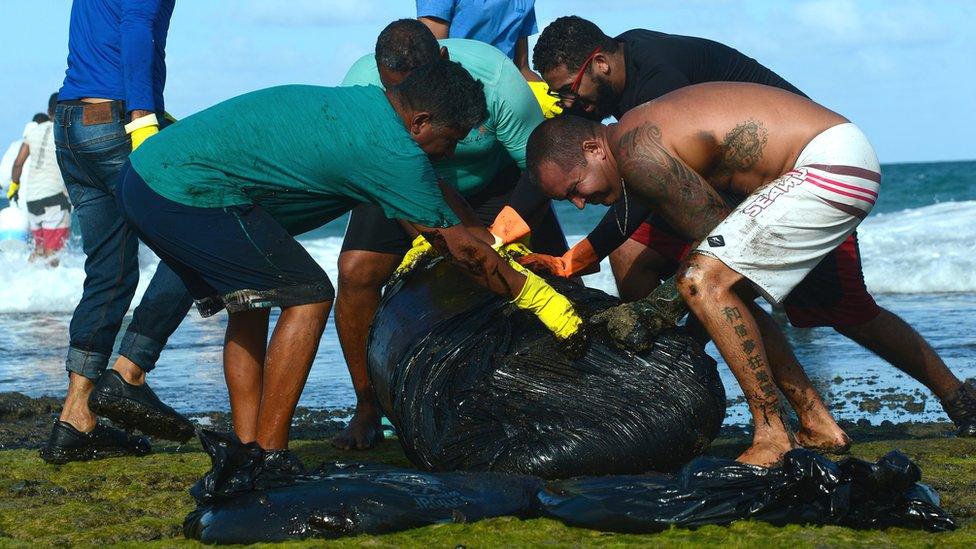 People rolling a large clump of thick oil