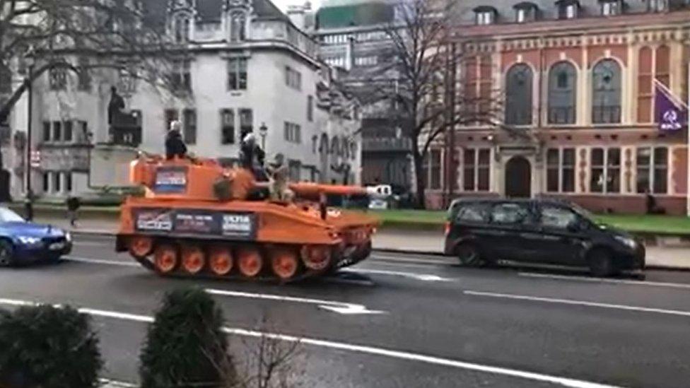 Orange tank driving past buildings in Parliament Square