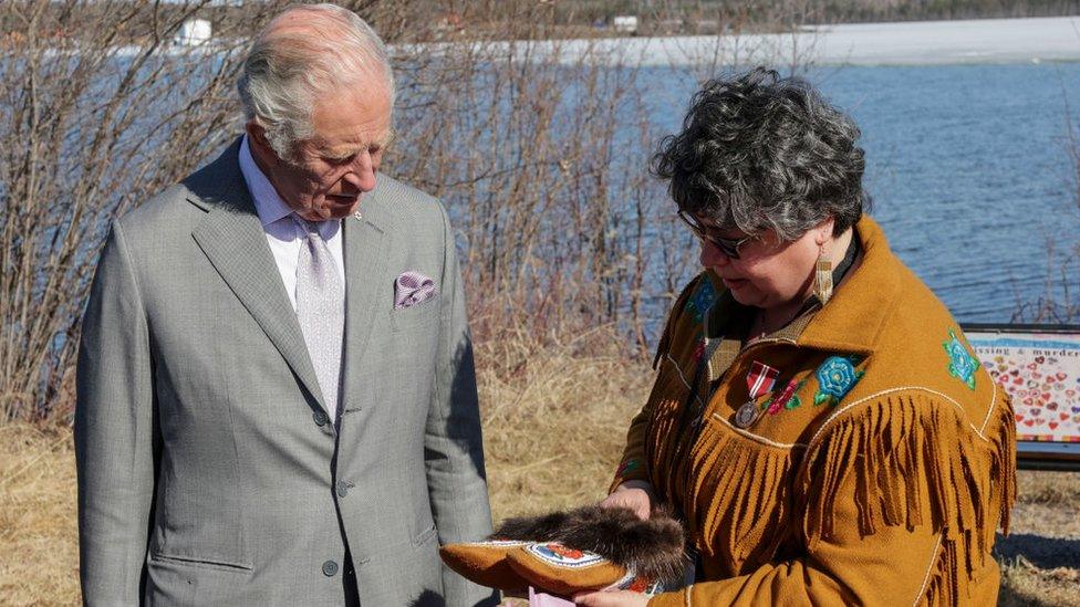 A woman shows Prince Charles a traditional Dene shoe, decorated with colourful stitching and a fur trim