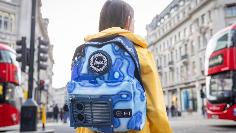 Eleanor facing away from camera, wearing rucksack. London background.