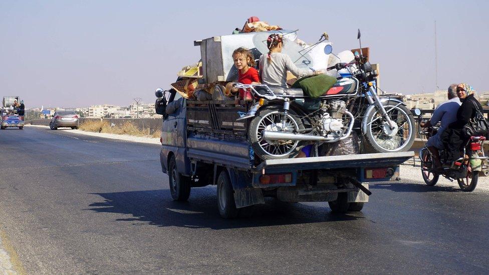 Children ride on the back of a van loaded with possessions as it drives along the Damascus-Aleppo highway in Idlib province (11 September 2018)