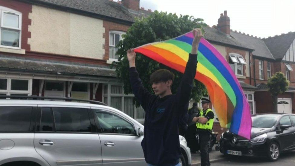 Protester with rainbow flag outside Anderton Park