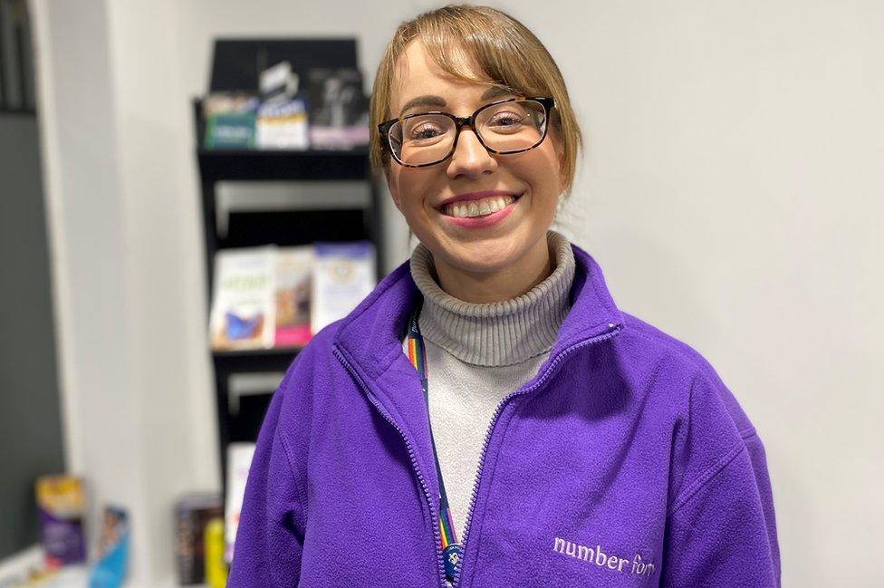 A woman in glasses smiles at the camera