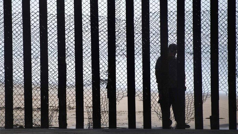 A man is seen standing on the Mexico side of a border fence separating the US at Border Field State Park in San Diego, California.