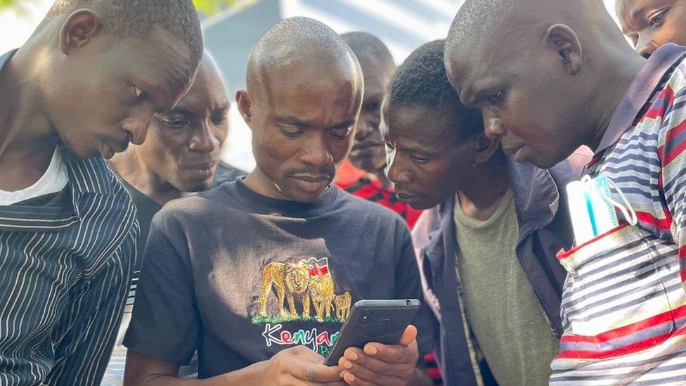 A group of men following updated on the elections on a mobile phone