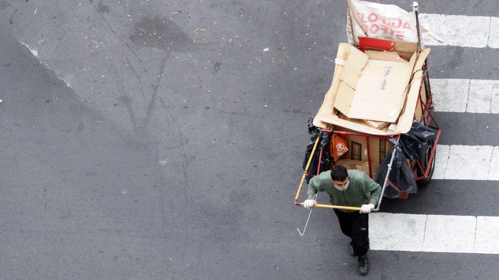 A waste worker is collecting rubbish bags along a street in Buenos Aires