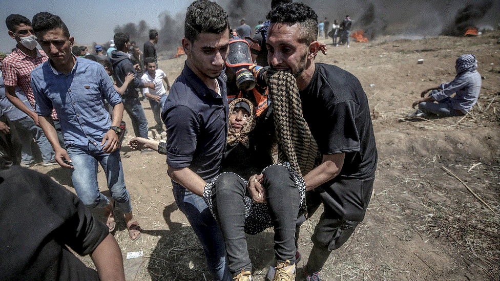 Palestinian protesters carry a wounded female protester during clashes after protests near the border with Israel in the east of Gaza Strip