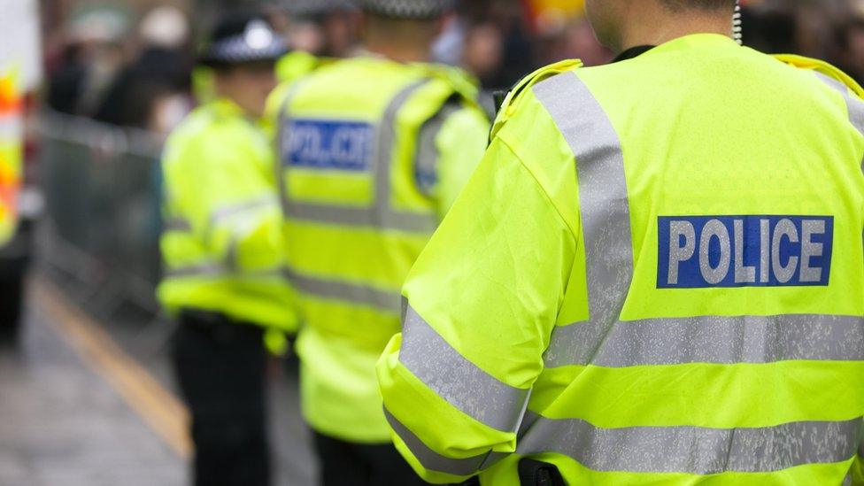 Three police officers in hi-vis jackets with Police written across the back