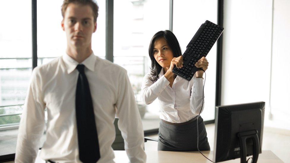 Woman raising keyboard to hit retreating manager