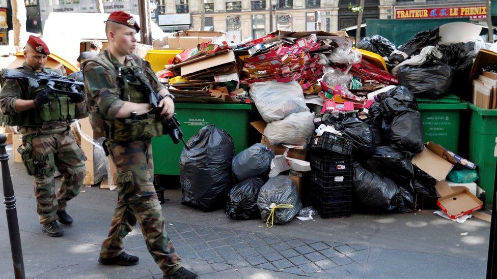 French soldiers pass uncollected rubbish in Paris, 9 June