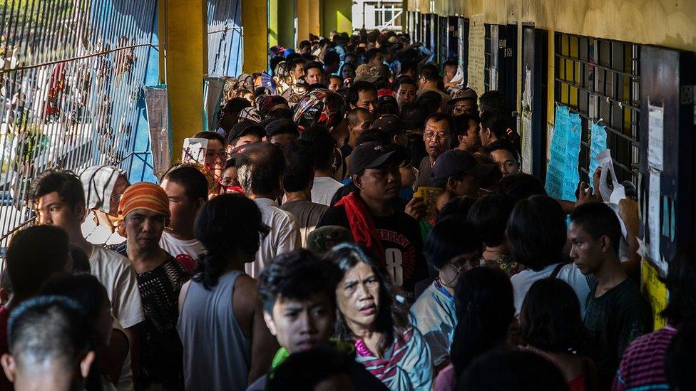 Dozens of people in a queue to vote at a polling station in Manila