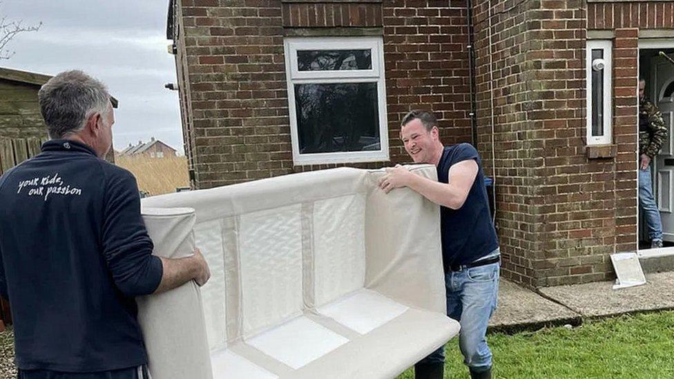 Men carry sofa into house