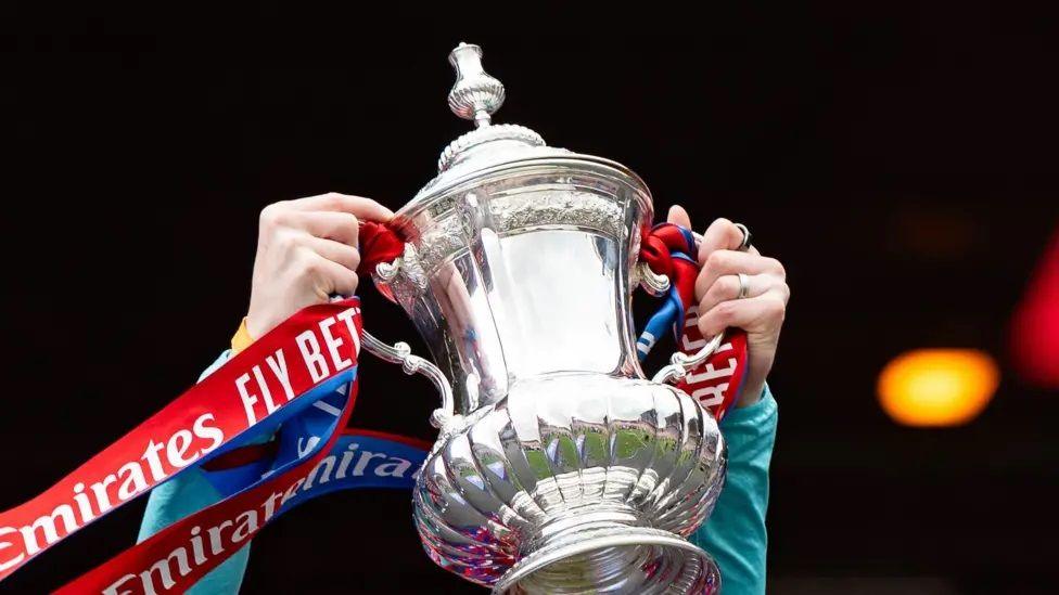 FA Cup trophy being lifted in the air