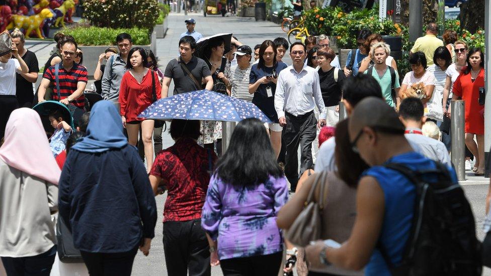 Pedestrians wait to cross the street along the Orchard Road shopping district in Singapore on February 21, 2018.