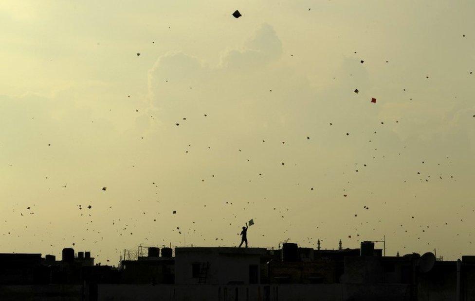 In this Aug. 15, 2013 file photo, a boy flies a kite from the roof of a house as other kites seem to flock in the sky above as Indians celebrate Independence Day in New Delhi, I