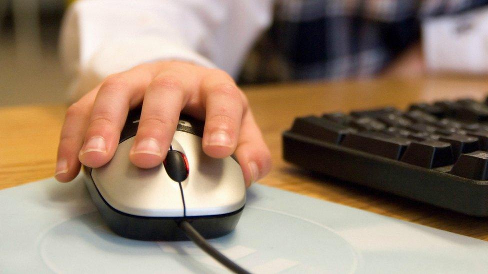 The hand of a child on a computer mouse