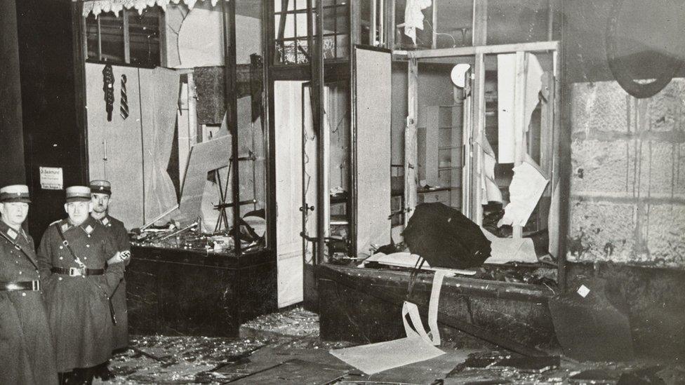 A destroyed shopfront with Nazi officers standing by