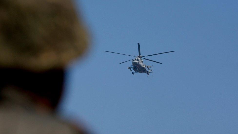 An Indian helicopter flies above the base in Pathankot