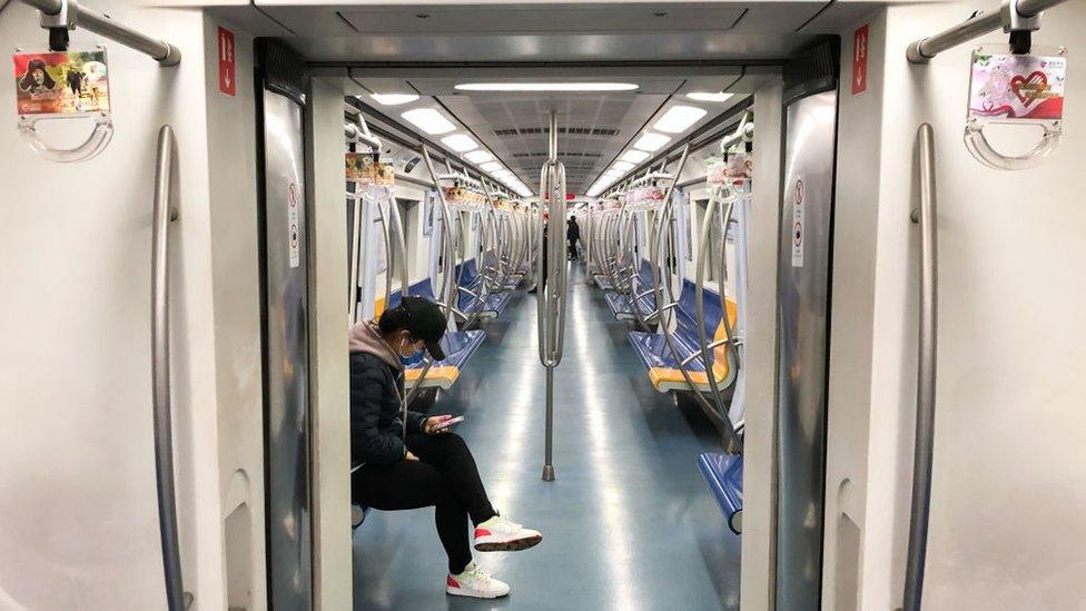 A man wearing face mask sits in a train carriage