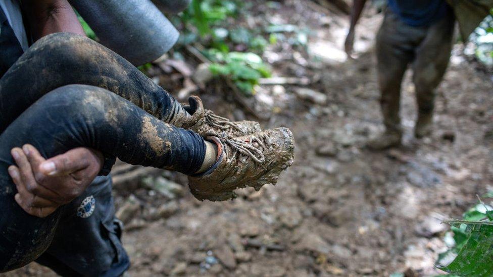 A Colombian guide carries a Haitian child up a mountain slope near Colombia's border with Panama on October 19, 2021 in the Darien Gap, Colombia.