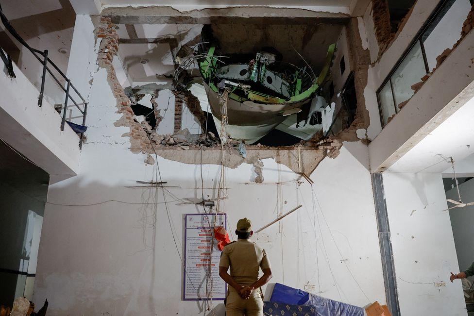 A police officer stands in front of debris at the crash site after an Air India aircraft, bound for London's Gatwick Airport, crashed during take-off from an airport in Ahmedabad, India June 12, 2025.