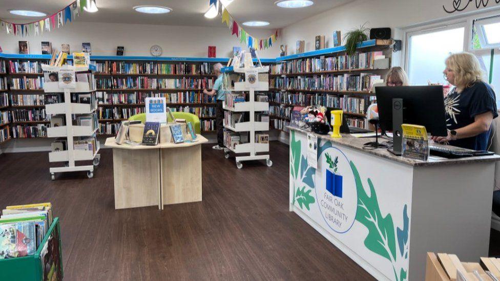 Librarian desk to right with shelves of books in the background and bunting hanging from the ceiling