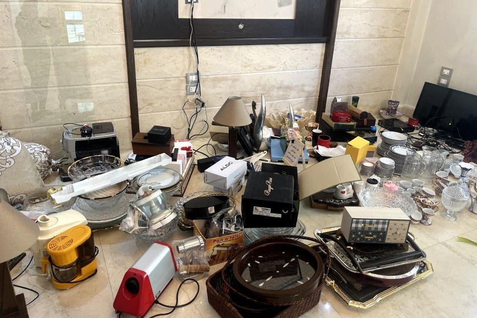 Utensils and home appliances are placed on the floor, piled together