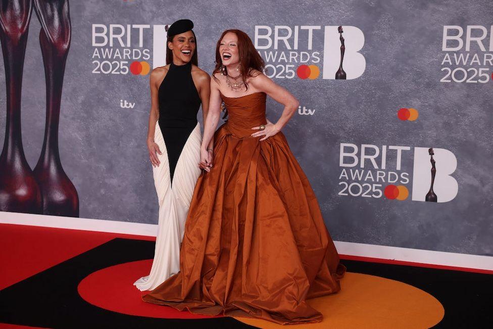 Alex Scott in a black and white outfit and Jess Glynne in a burnt orange dress